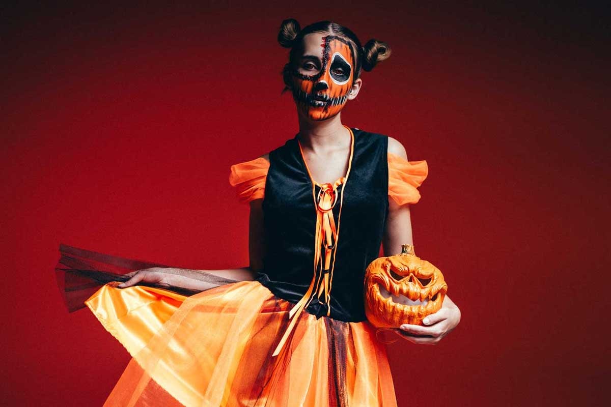 Eine Dame im orangefarbenem Hexenkostüm