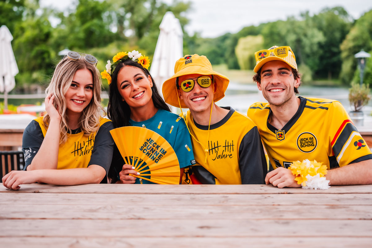 Vier fröhliche Menschen am Tisch in Jeck im Sunnesching Outfits und Accessoires von Deiters