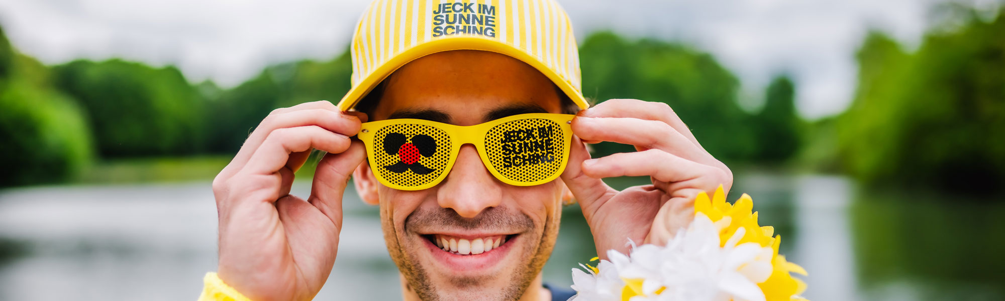 Mann mit Jeck im Sunnesching Brille und Basecap am See